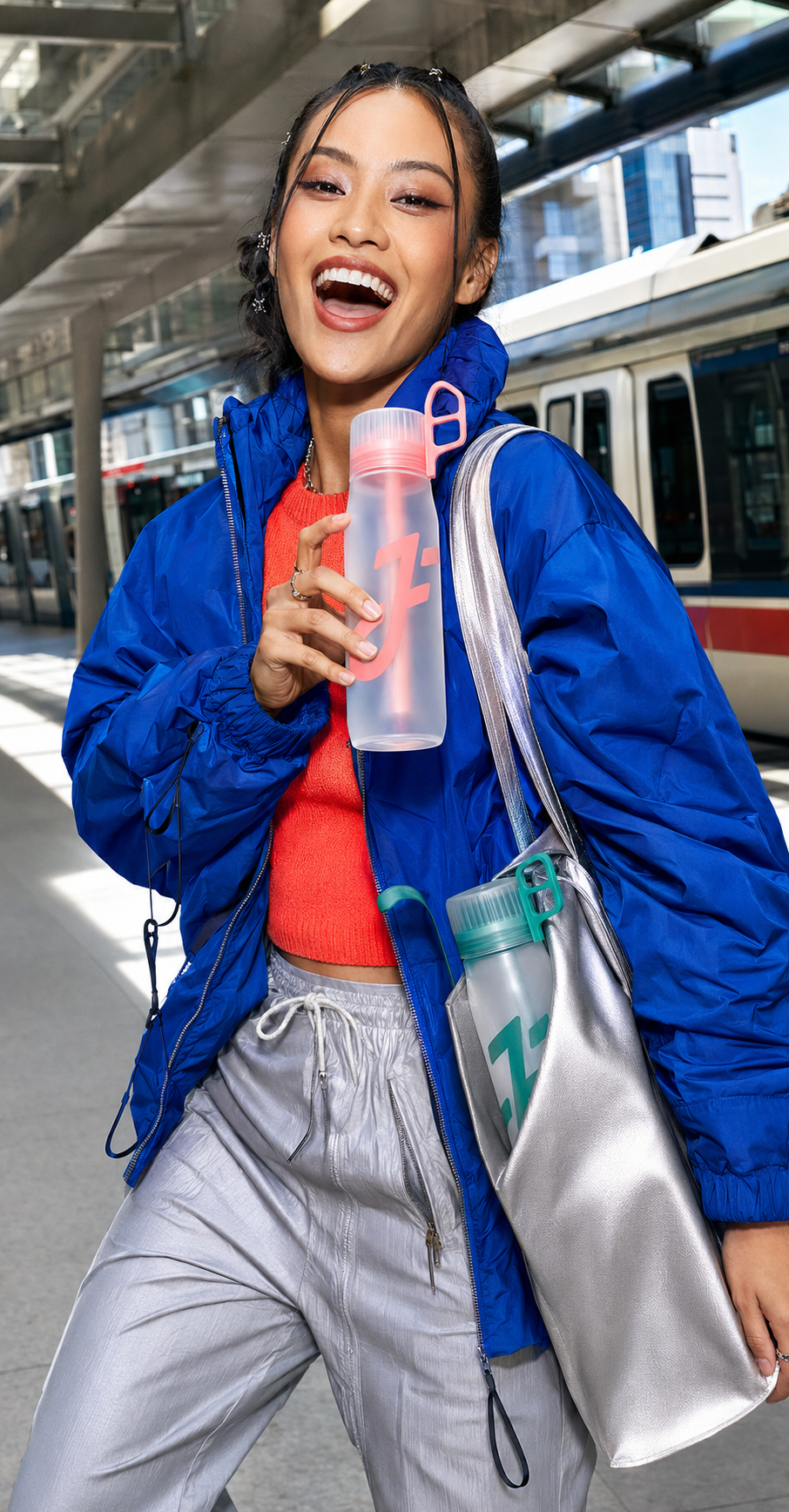 Adult woman carrying coral and emerald FORA bottles through the city